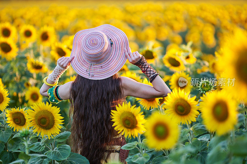 美丽的女人在向日葵地里享受自己