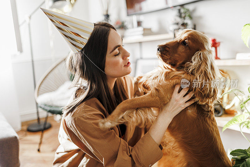 美丽的女人和她的狗狗在家里庆祝她的狗狗生日。