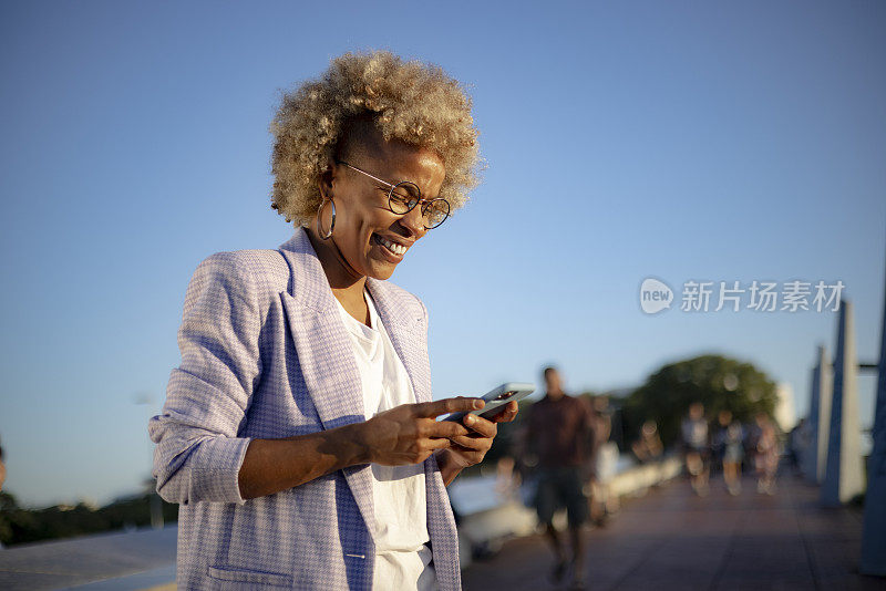 年轻的西班牙裔黑人女性在户外使用智能手机