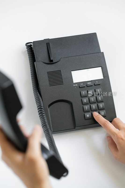 员工手按电话桌上的号码键联系客户或接听电话，热线概念