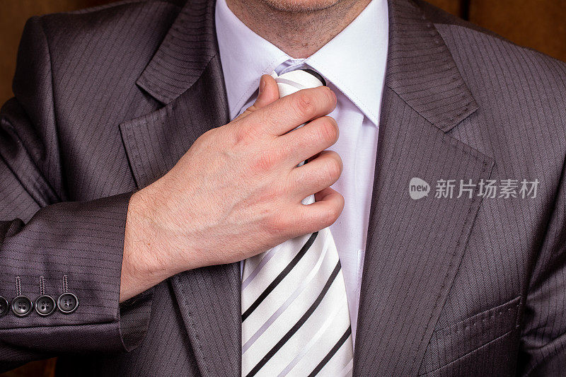 商人正了正领带。男士穿着黑色西装，衬衫和领带，燕尾服