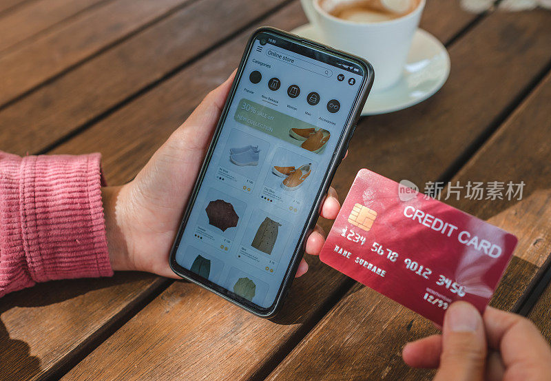女人在户外用信用卡在咖啡店网购。近手持智能手机