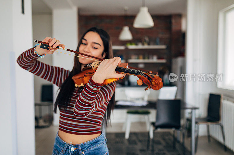 一个有才华的女小提琴手站着练习拉小提琴的特写。