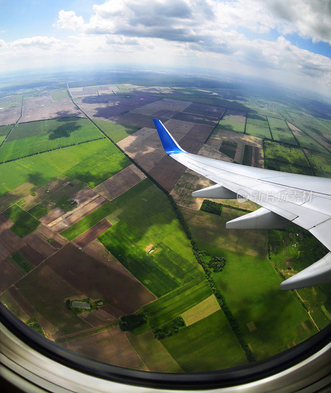 从飞机的舷窗看到棕色和绿色的田野