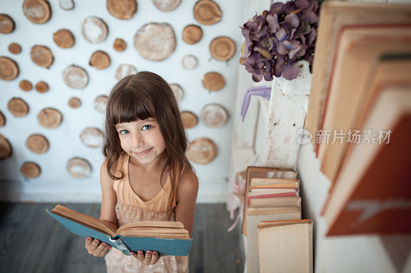 小女孩微笑着读着书;
