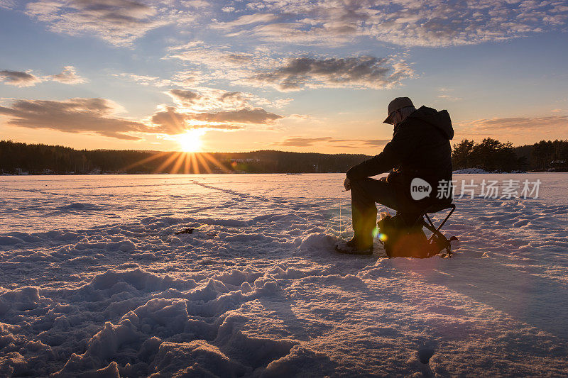 日落时在挪威的一个湖上冰上钓鱼。