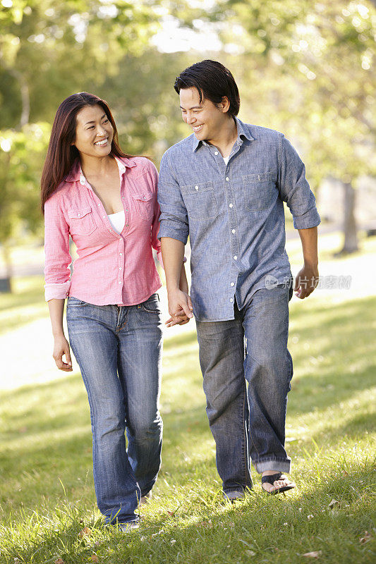 亚洲夫妇手牵着手在公园散步