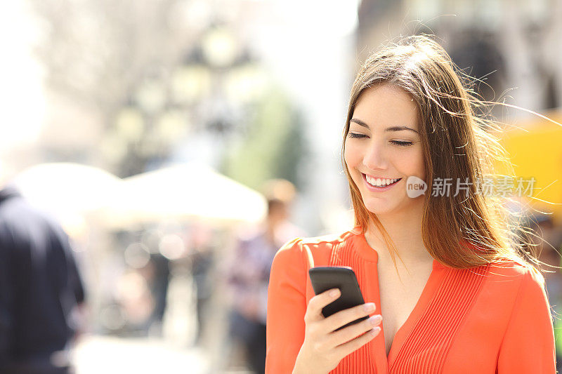 穿橘色衬衫的女人在用智能手机发短信