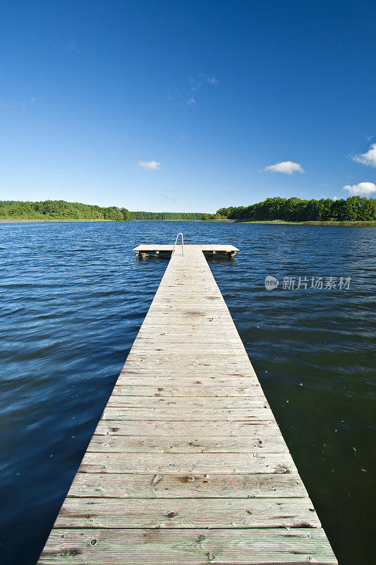 多云的夏日天空下湖上的木板路码头