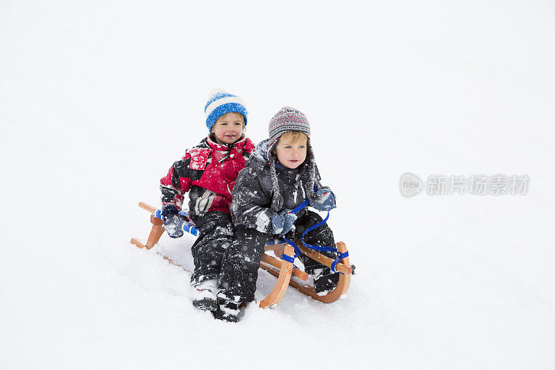 两个小男孩在雪地上拉雪橇