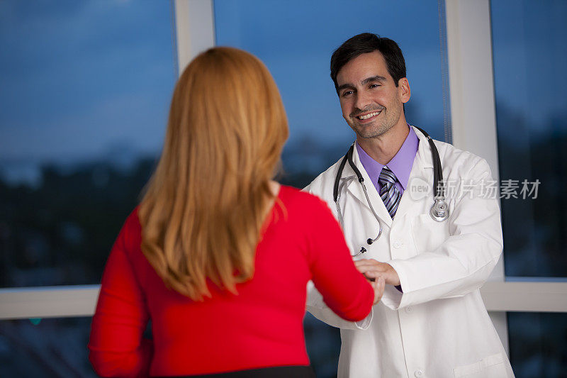 微笑的医生与女性在办公室握手