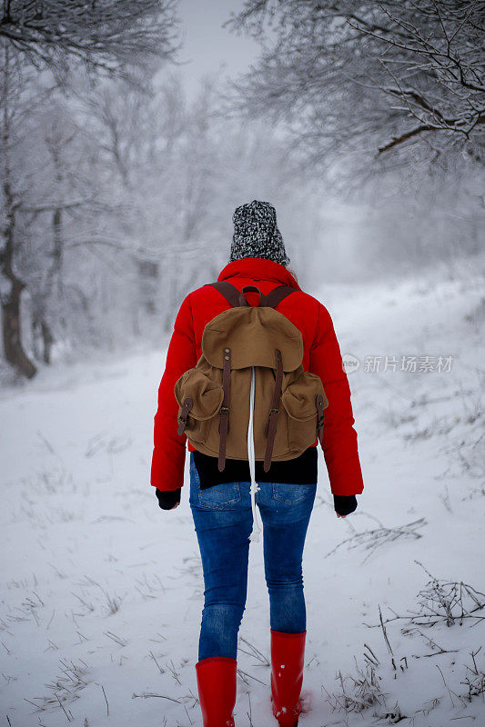女徒步旅行者背包和雪鞋在雪地上的雪鞋