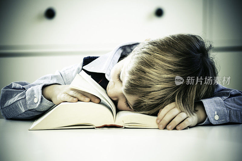小男孩睡在一本书上