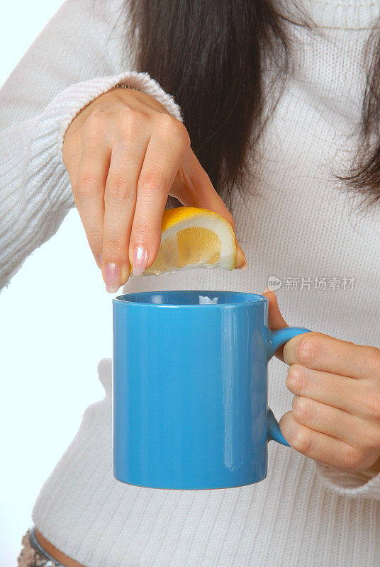 迷人的黑发女子在茶杯里挤柠檬汁