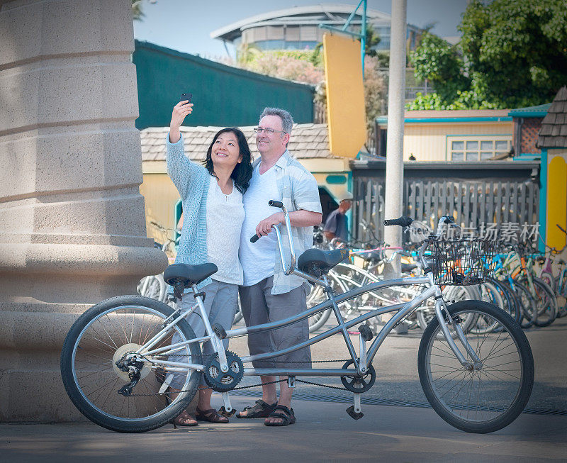 成熟的，混合种族夫妇与双人自行车自拍