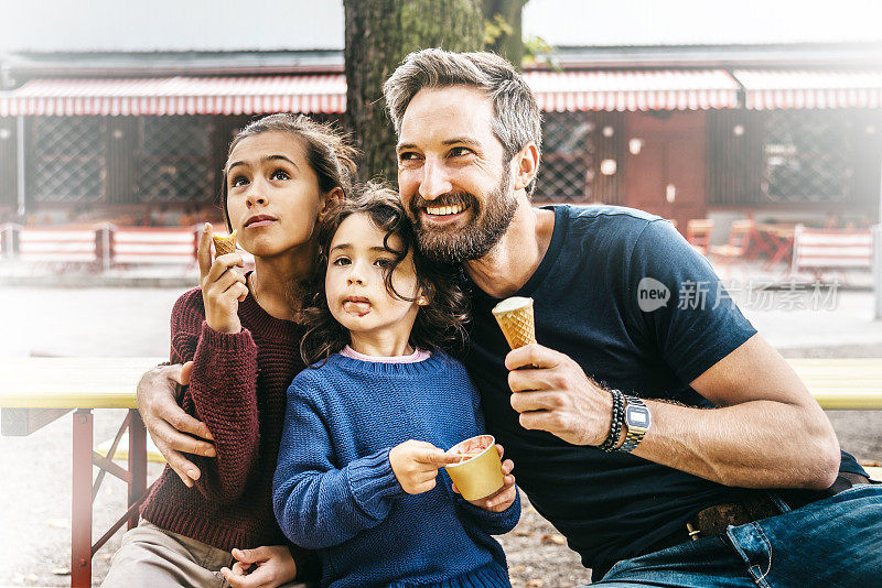 大笑的父亲和两个女儿在街上吃冰淇淋