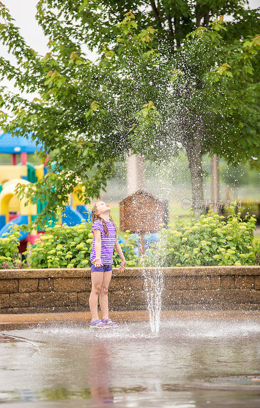 小女孩在水花公园的喷泉里玩耍