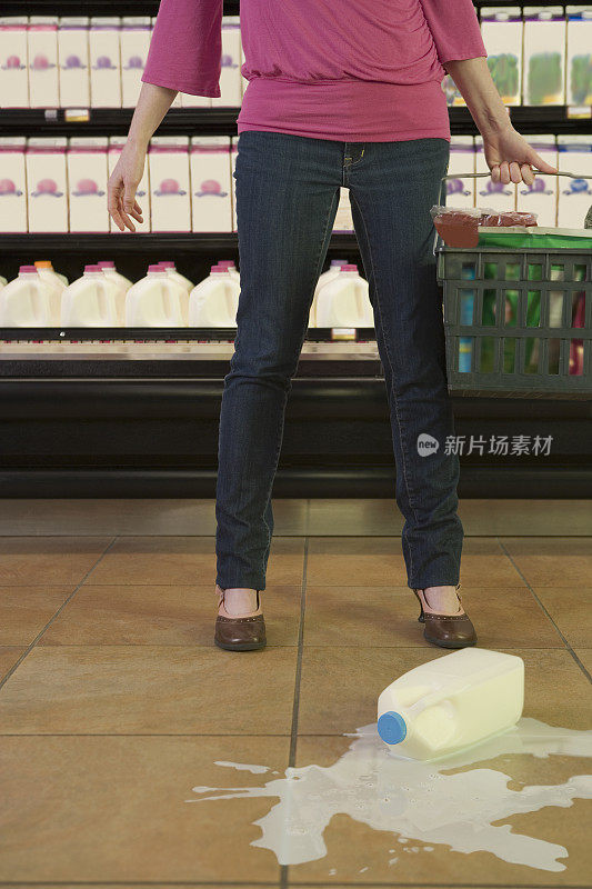 中年妇女在超市里站在打翻的牛奶旁