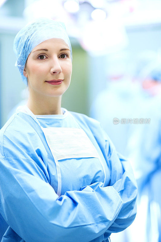 快乐的女外科医生双臂交叉站在手术室里