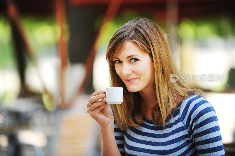 年轻女子在巴黎路边咖啡馆喝浓缩咖啡