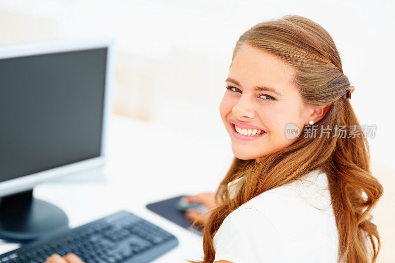 快乐的女商人在电脑前工作，面带微笑