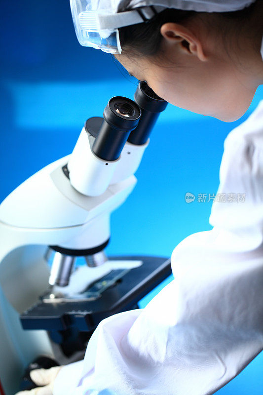 女科学家通过显微镜检查载玻片