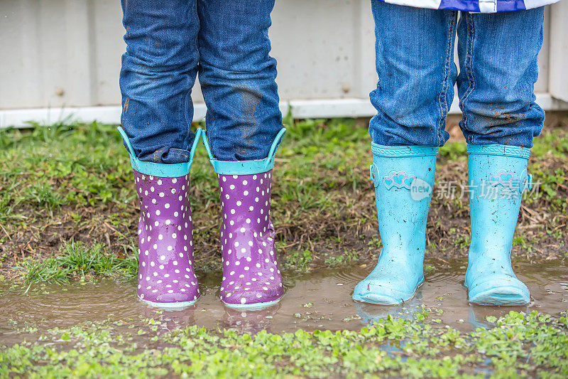 农场水坑里的两个年轻女孩的雨靴