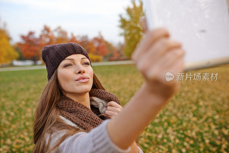 美丽的年轻女子和她的数字平板电脑在公园里