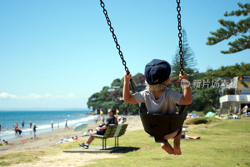 夏天，一个孩子在海滩公园荡秋千