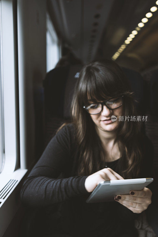 年轻女子在火车上使用平板电脑