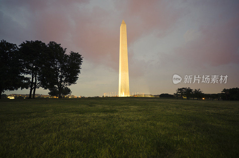 日落后的华盛顿纪念碑，底部是美国国旗