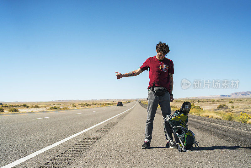 年轻人，搭便车的人，想在犹他州沙漠的高速公路上搭车