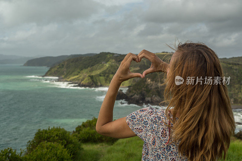 海边的一个女人做了一个心形的手指架