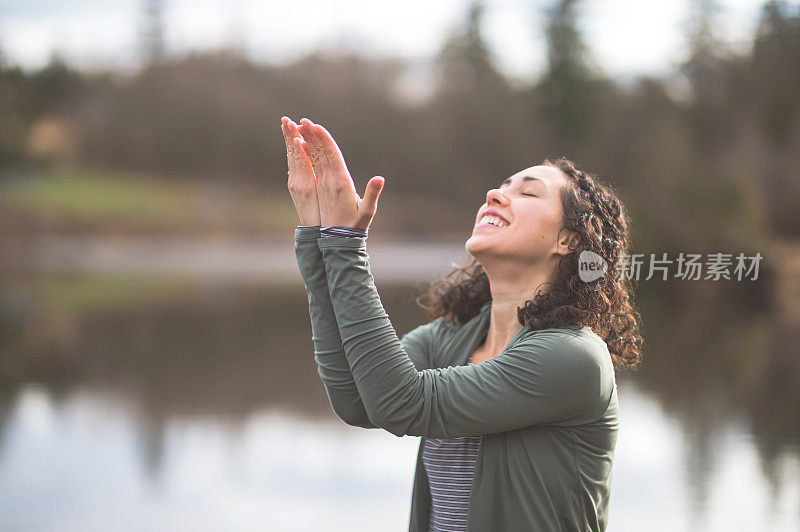 年轻的妈妈在湖边做瑜伽