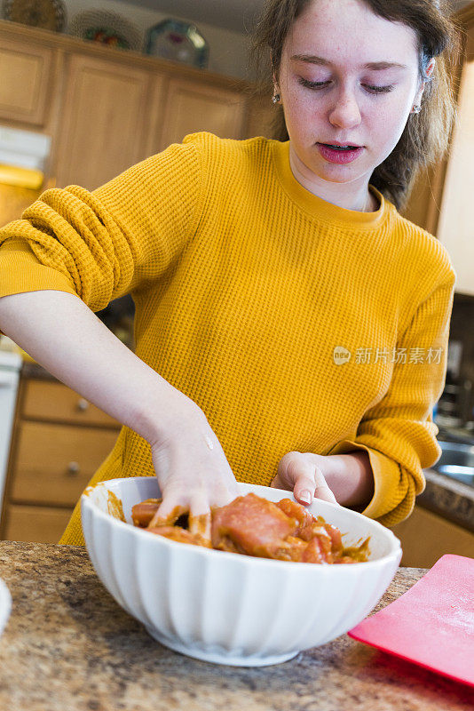 一个十几岁的女孩在厨房里腌制烤牛肉