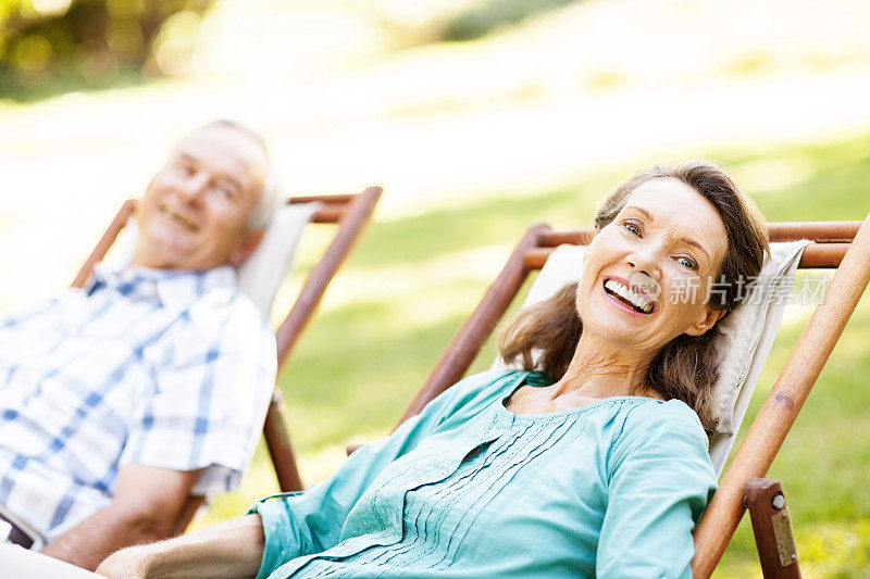 愉快的老妇人斜倚在花园的躺椅上