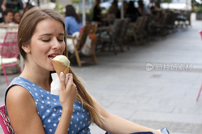 一个漂亮的女孩正坐在咖啡馆里吃冰淇淋