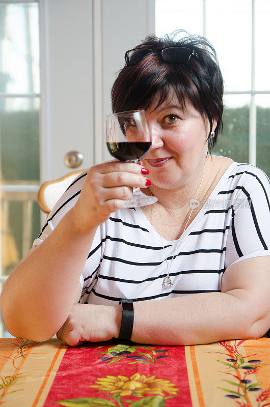 矮胖女人用红酒敬酒透过她的杯子