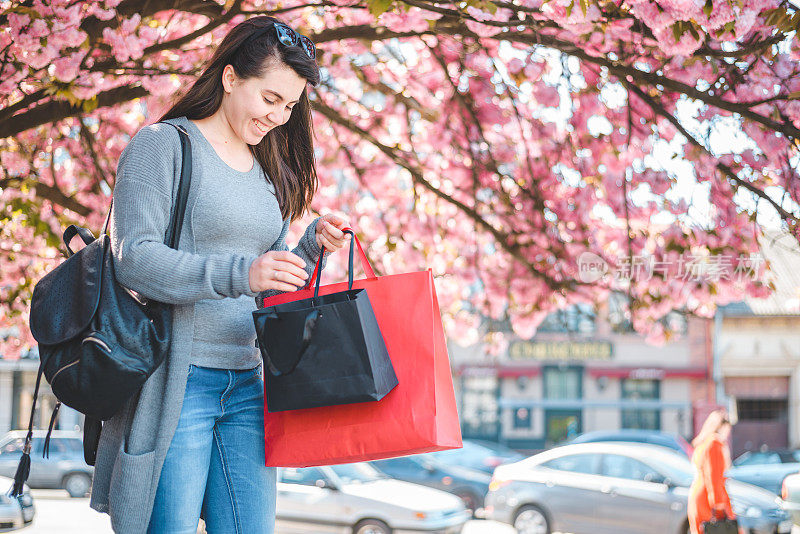 快乐的女孩与购物袋下盛开的樱花