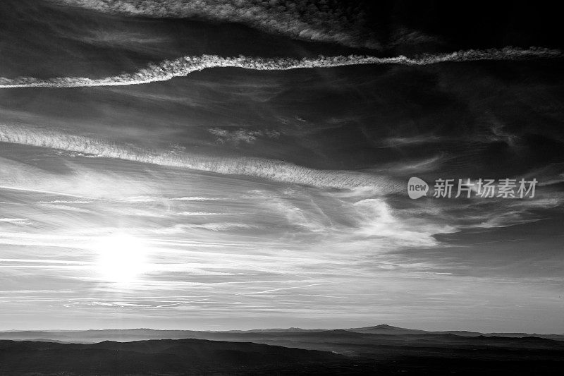 夕阳越过远山，天空布满了白云和蒸汽的痕迹