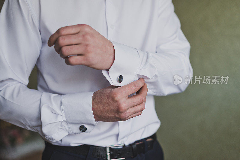 男人在他的衬衫袖子上扣上袖扣1182。