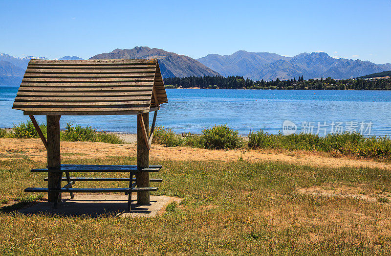 夏日的阴影庇护游客在瓦纳卡湖，新西兰与蓝色的湖和山的背景。