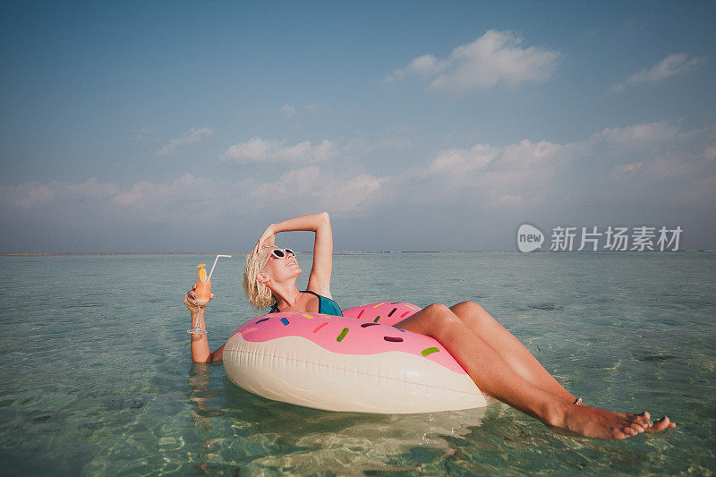 性感的女人浮在水上，有鸡尾酒时间在海洋，马尔代夫