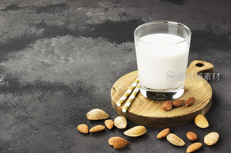 纯素杏仁牛奶在玻璃在一个黑暗的背景。市面上的牛奶。副本的空间。食品的背景