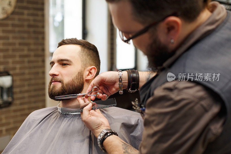 理发师在理发店用剪刀给顾客修剪胡须
