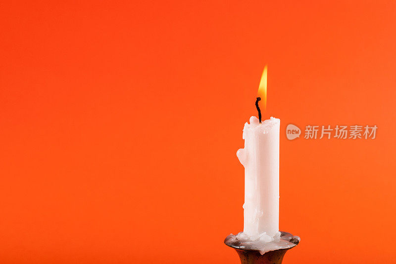 蜡烛燃烧在橙色的背景和空间设计。近距离