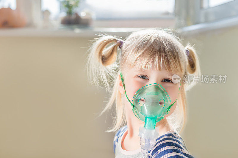 快乐微笑的孩子使用雾化面具。吸入性疗法治疗胸寒咳嗽。保健和疾病预防的概念