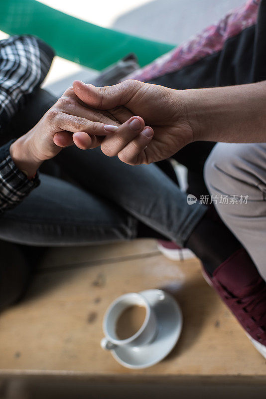 近距离拍摄一对不认识的夫妇在咖啡馆牵手。