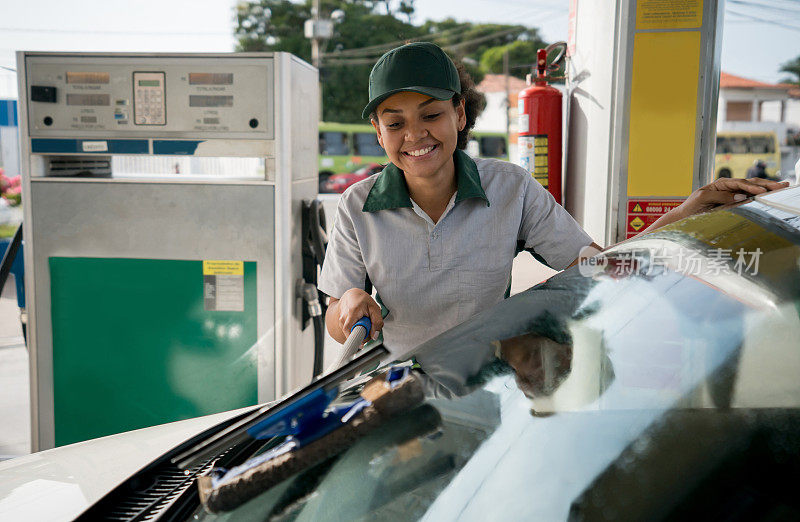 一名女服务员在加油站清理挡风玻璃
