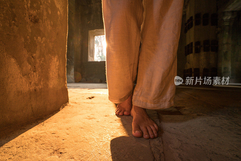 近距离拍摄在日落时分，柬埔寨吴哥窟的古庙中赤脚行走的女子